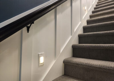 Completed staircase with wainscoting, carpet and custom handrail