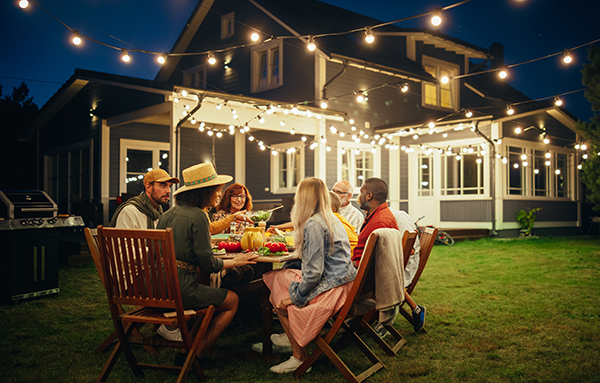 dinner party gathering on lawn in front of well maintained house