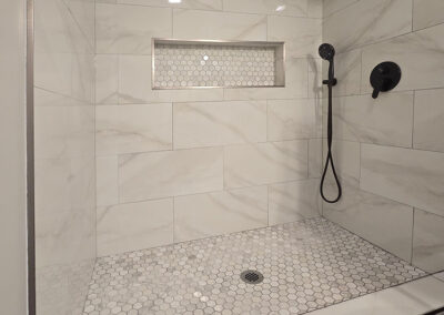 fully renovated shower stall with new marble tile on the sides and floor
