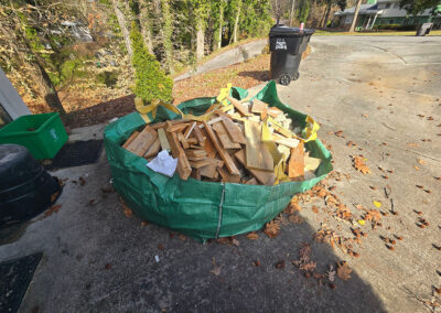 bathroom demolition materials in a green dumpster bag on a driveway